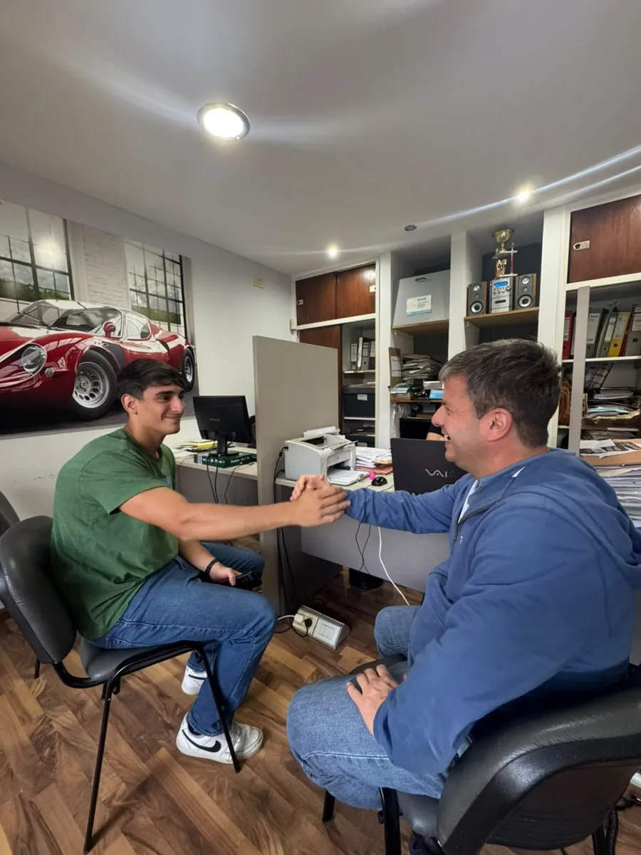 Un cliente y un vendedor se dan la mano sentados en la oficina del local