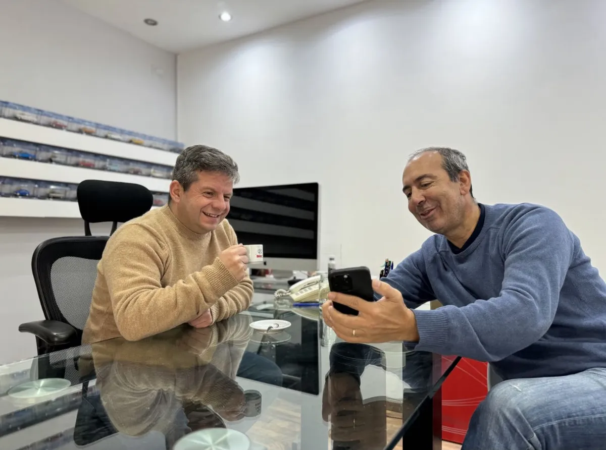Un cliente le muestra el celular a Juan Manuel en la oficina