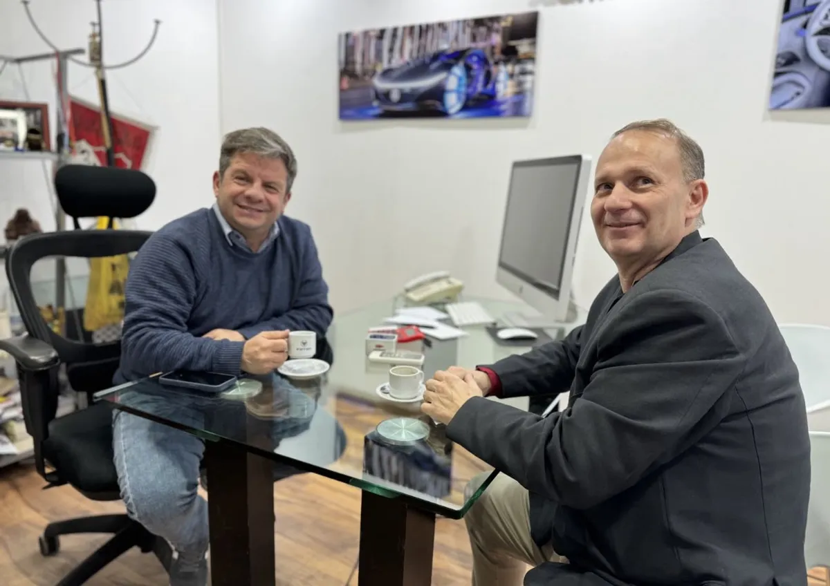 Juan Manuel conversando con un cliente en la oficina, café de por medio